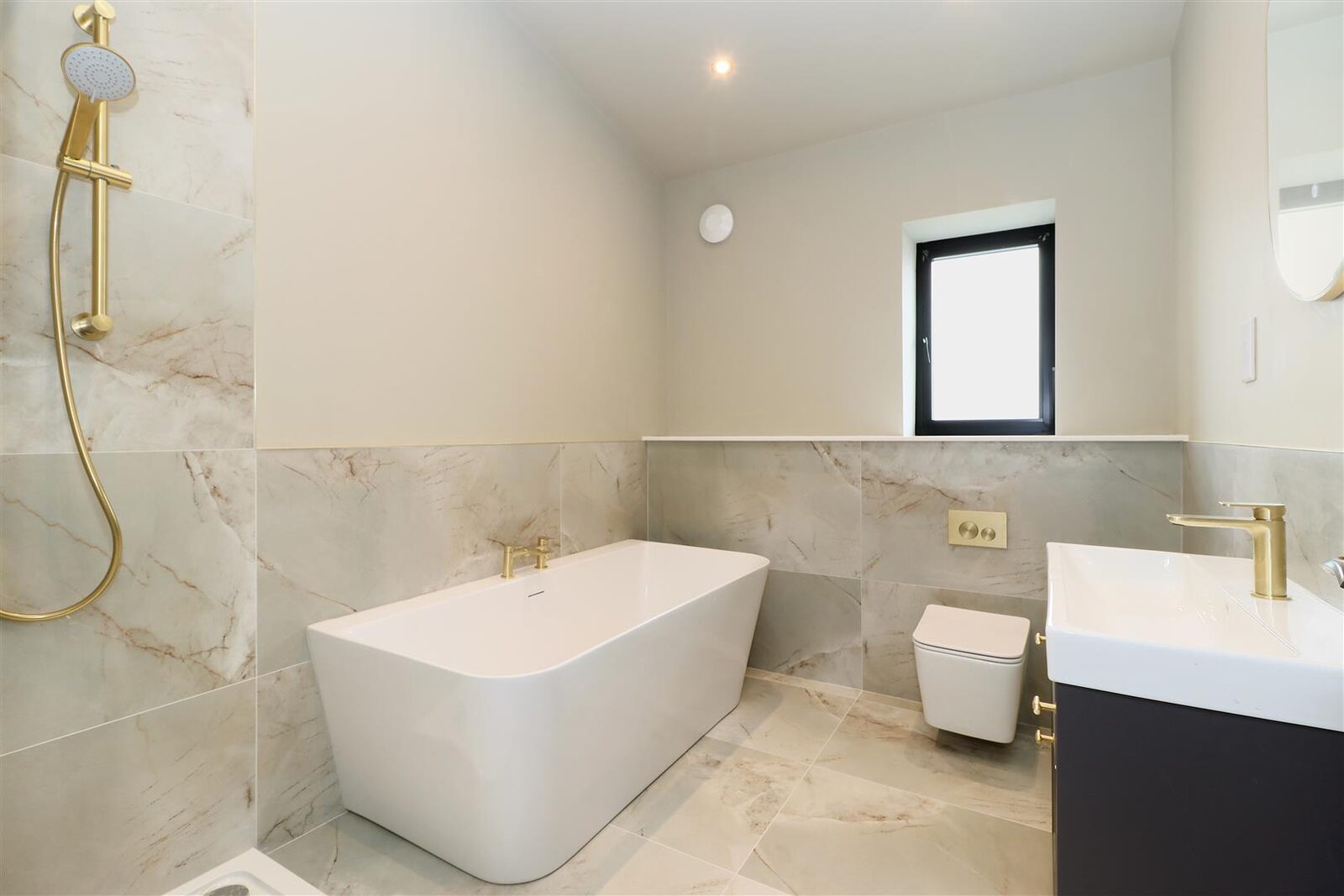 Freestanding bath with brass fittings and marble effect tiling
